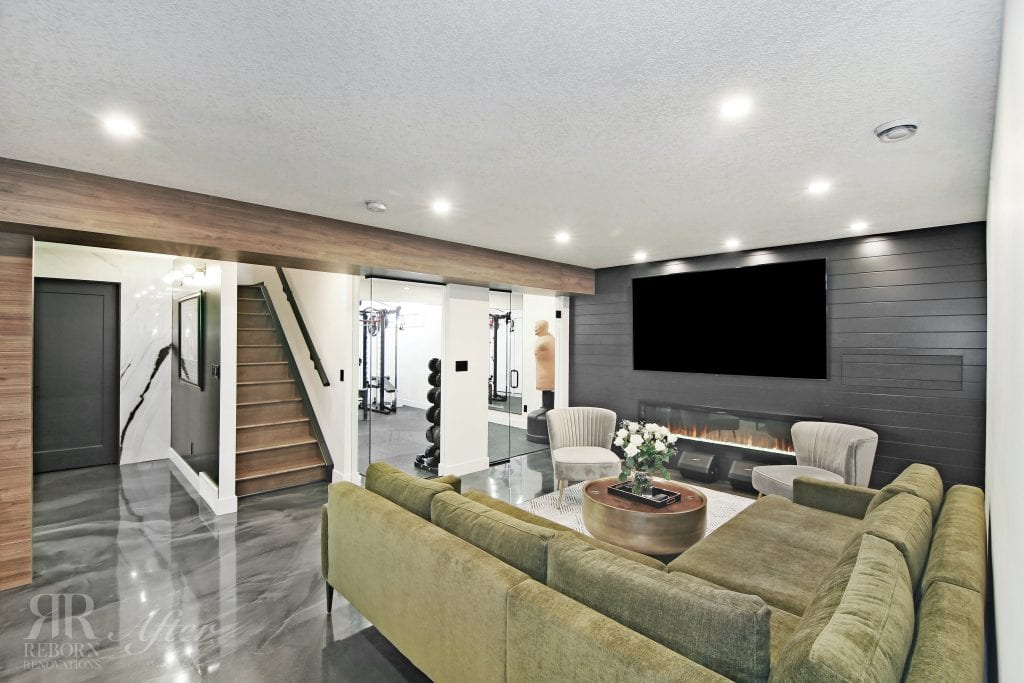 A basement development in the Hamptons neighbourhood of Calgary featuring a green couch and a TV in the living room.