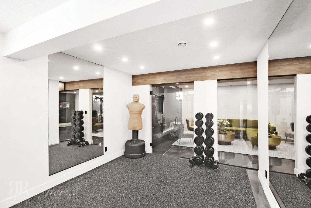A Hamptons basement development with a gym room featuring mirrors and a punching bag.