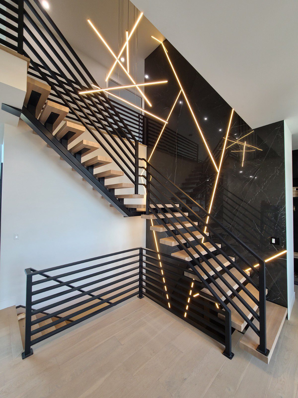 A modern black-railing staircase in a De Winton Development home.