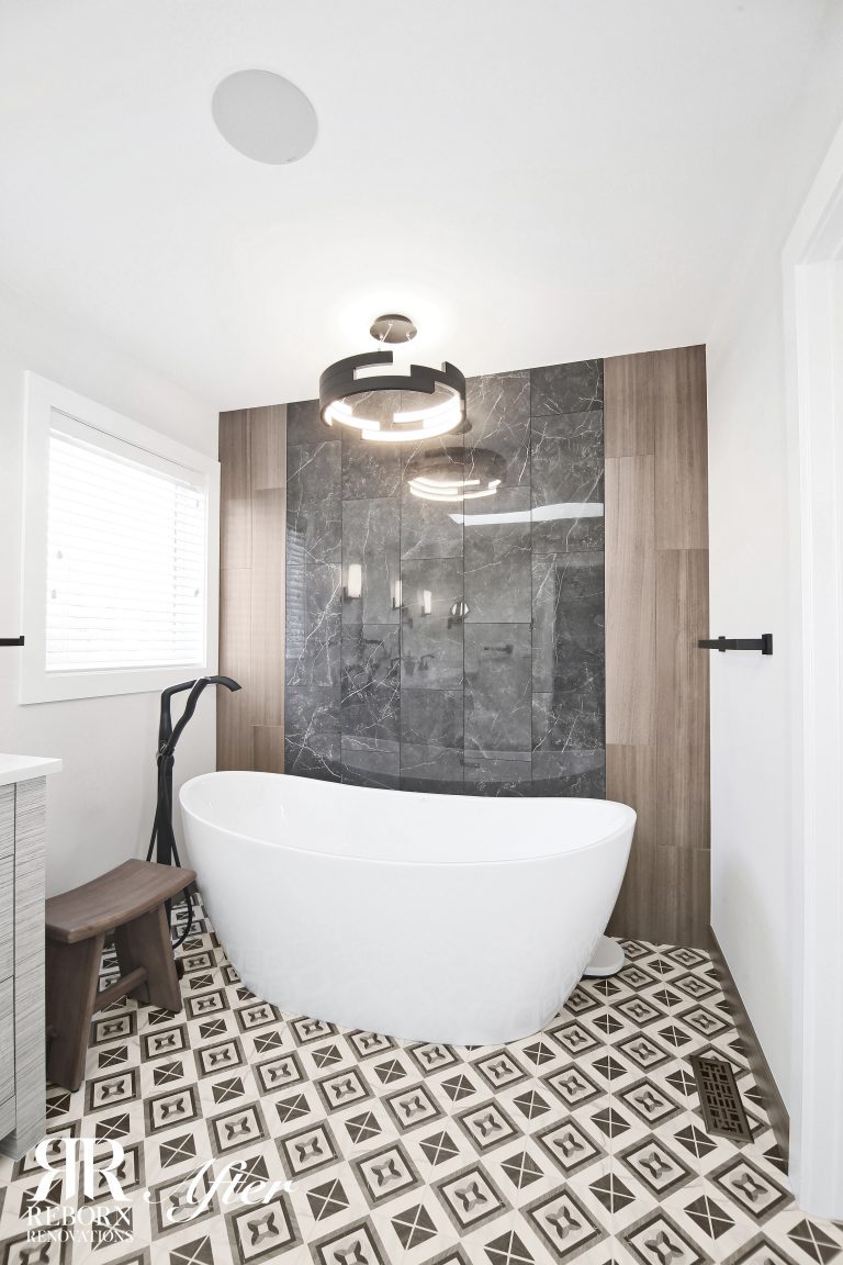 A remodeled bathroom with black and white tile and a bathtub.
