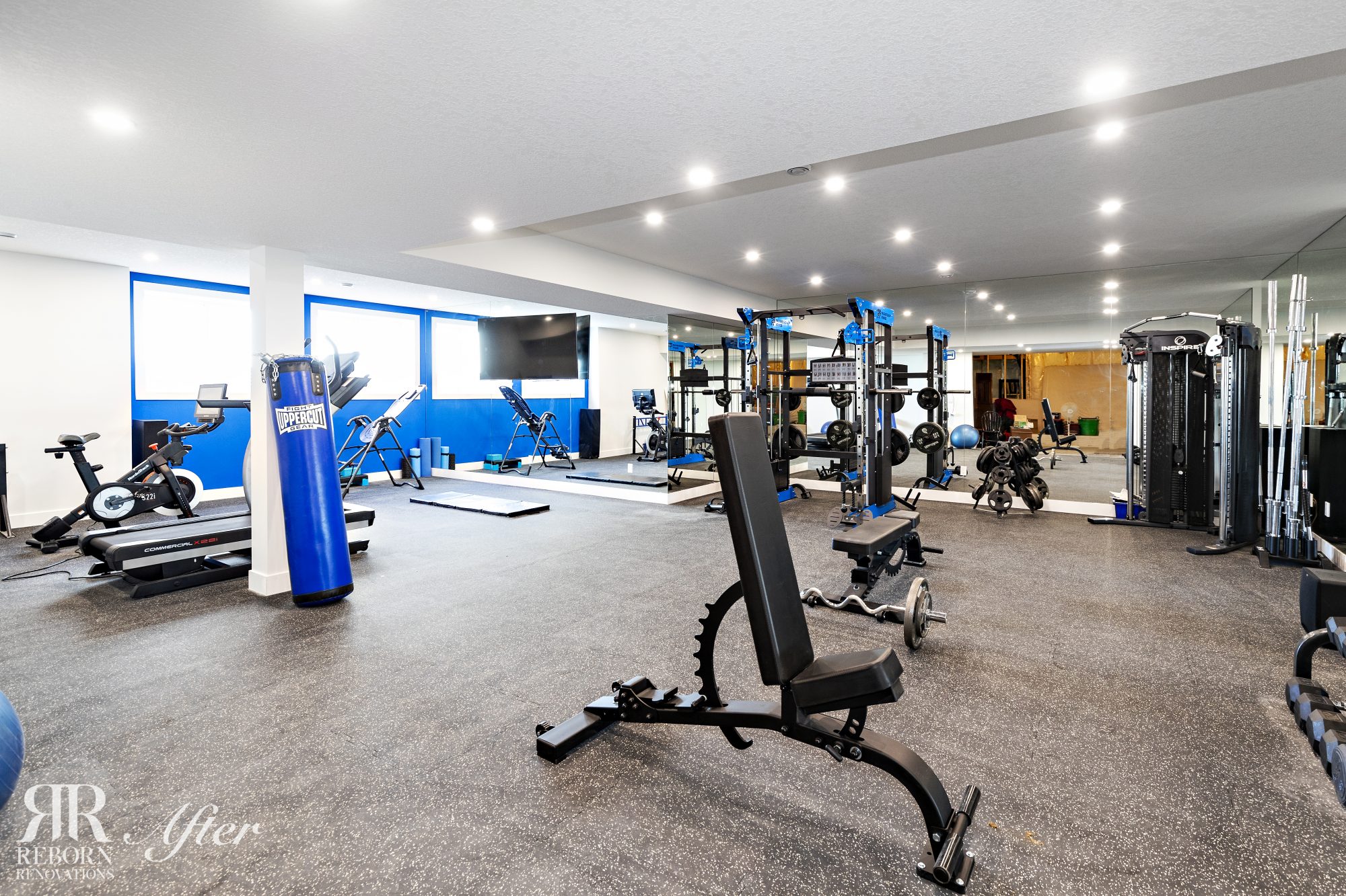 A basement gym with workout equipment in it.