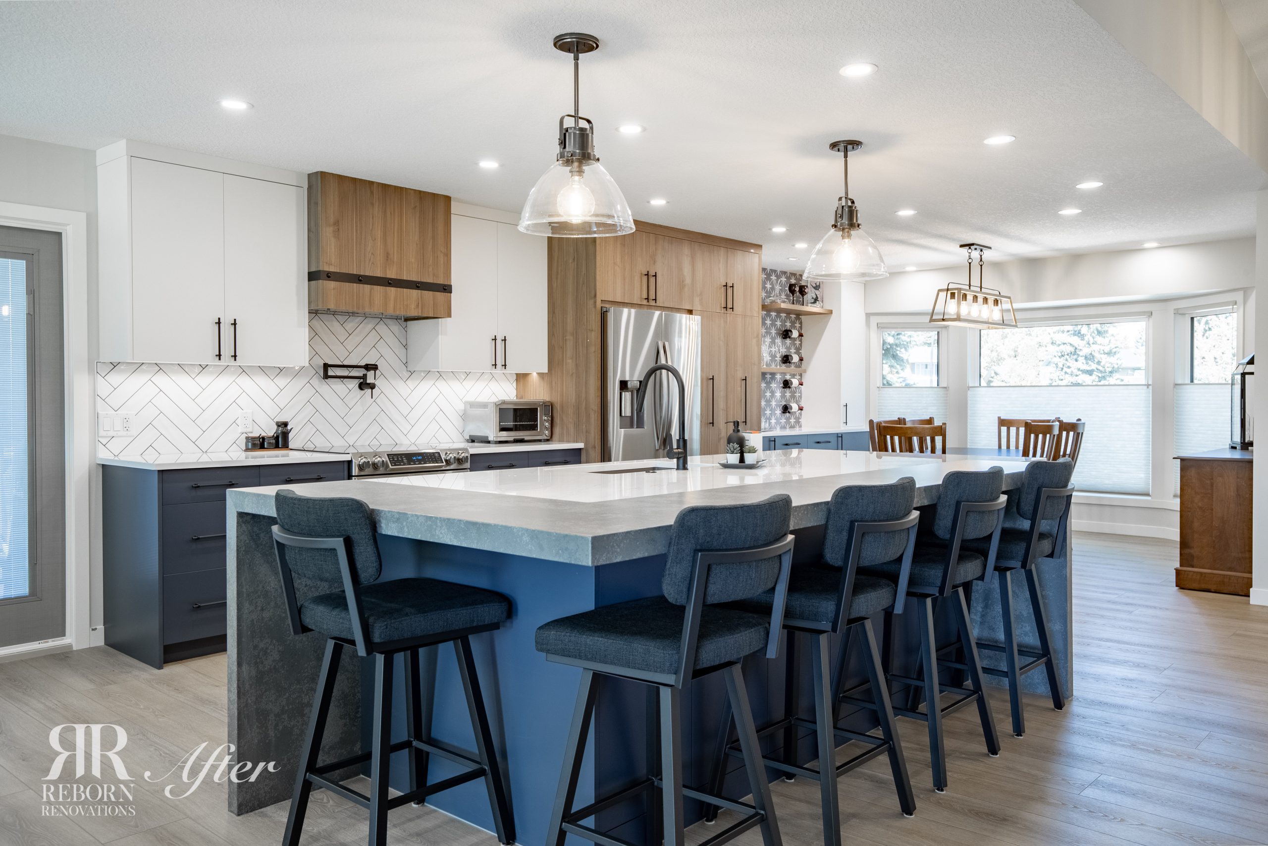 A newly completed home renovation, including kitchen remodel, with a large island and bar stools. Completed by Reborn Renovations