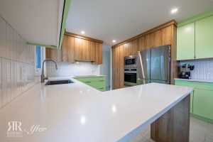 A kitchen with green cabinets and white counter tops.