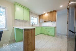 A kitchen with green cabinets and white counter tops.