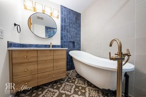 A bathroom with a bathtub and blue tiled walls.