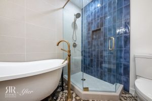 A blue tiled bathroom with a tub and shower.