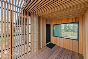 An wildwood house with wooden slats and a glass door undergoing an exterior remodel.