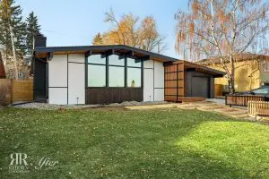 A modern Wildwood home with a backyard surrounded by trees and grass, undergoing an exterior remodel.
