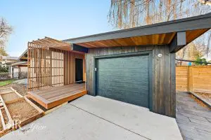 A Wildwood home with a modern exterior remodel featuring a wooden garage door.